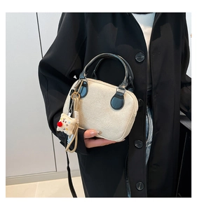 Detail of beige velvet pillow bag with black handle and a cute plush square charm