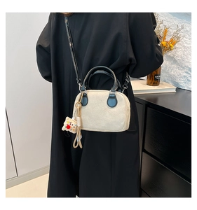 Detail of cream velvet pillow bag with black leather handle and cute yellow charm