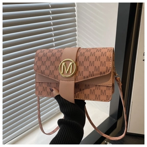 Close-up of golden M-logo buckle and monogram pattern on a pink leather crossbody bag