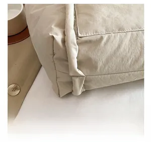 Close-up of precise stitching and quilted nylon texture on a beige tote bag