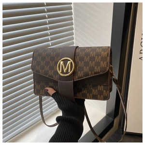 Detail of vintage brown shoulder bag with M pattern and golden metal buckle