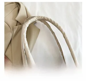 Detail of padded beige nylon shoulder strap on tote bag with comfortable ruched design