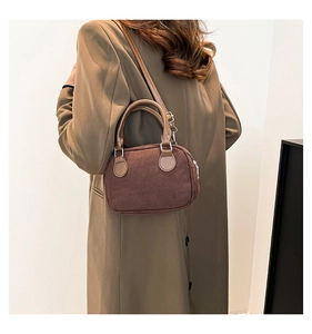 Detail of dark brown matte suede texture and smooth leather handle on a bowling bag