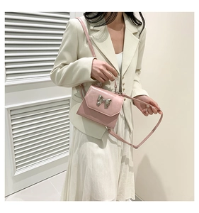 Detail of pink crossbody bag with silver bow ornament worn with elegant outfit