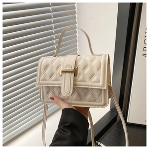 Dettaglio borsa trapuntata beige con chiusura a H dorata tenuta in mano