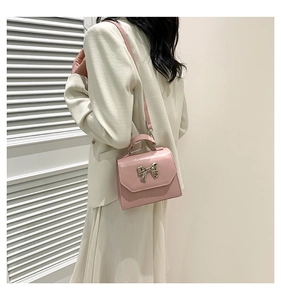 Vue latérale d'un sac rose avec nœud argenté porté sur une veste de couleur crème
