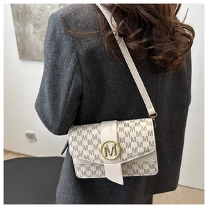 Detail of off-white underarm bag with M-pattern and gold metal buckle on gray blazer