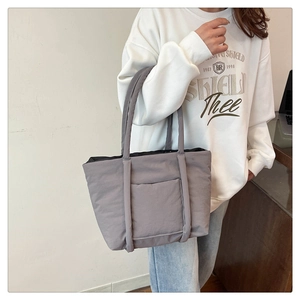 Detail of grey quilted tote bag with front pocket and comfortable wide handles