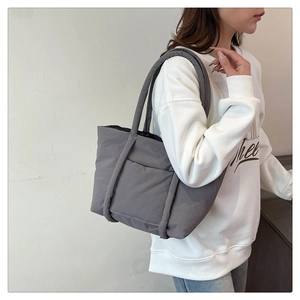 Detailed side view of large grey quilted tote bag with padded shoulder straps