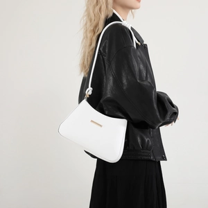 Minimalist white leather underarm bag with gold hardware shown on a model