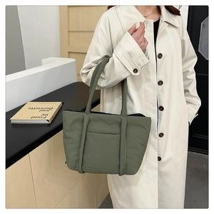 Detail of olive green quilted tote bag showing matte texture and hidden front pocket