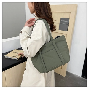 Deep green oversized quilted tote bag shown on model in a modern minimalist setting