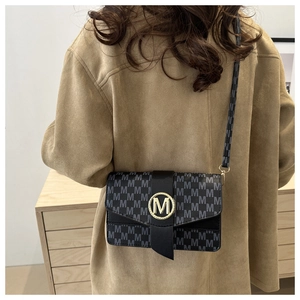 Close-up of black crossbody bag featuring grey monogram M pattern and gold metal buckle