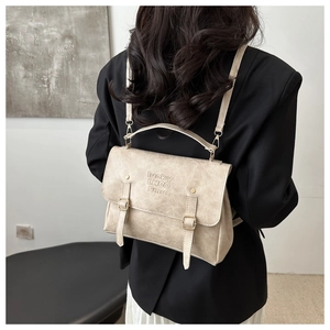Detail of beige textured leather backpack showing flap closure and embossed brand logo