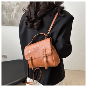 Detail of vintage brown PU leather backpack with buckle straps and embossed logo
