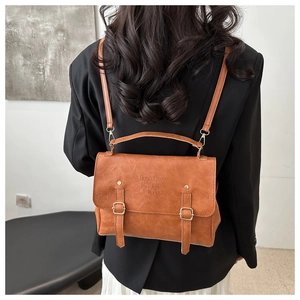 Dettaglio dello zaino vintage in pelle marrone con logo inciso e fibbie in metallo dorato