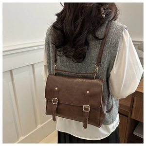 Detail view of the vintage brown faux leather backpack with metallic buckle and branding