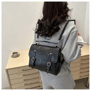 Détail du sac rétro en similicuir noir avec boucle dorée et logo embossé élégant