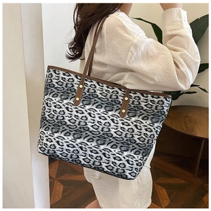 Détail du sac cabas léopard avec lanières en cuir marron et rivets dorés en métal