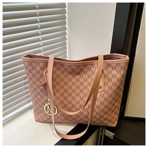 Close-up of pink tote bag featuring letter M monogram print and gold logo charm