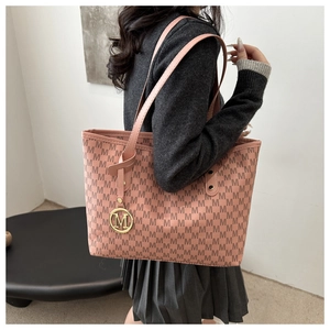 Close-up of pink tote bag with M letter pattern print and golden metal logo pendant