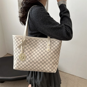 Minimalist beige tote bag with M letter print and gold pendant on model shoulder