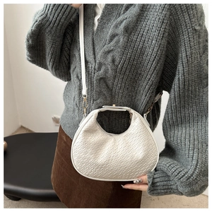 Detail of white crescent bag showing woven texture, gold hardware and leather strap
