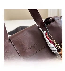 Detail of dark brown leather bucket bag with fashion stamp and plush bear charm decoration