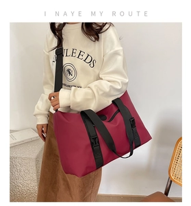 Detail of burgundy waterproof travel tote with reinforced black straps and functional buckles