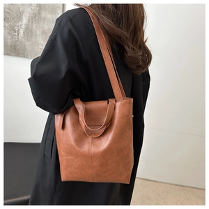 Close-up of brown tote bag with embossed logo and stitching detail for women