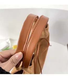 Close-up of brown suede tote bag with smooth leather handle and fine stitching detail