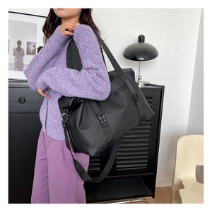 Close-up of black waterproof travel bag with adjustable strap on purple outfit