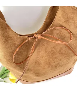 Detail of caramel suede tote bag featuring leather bow knot and premium texture finish