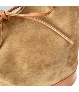 Detail of brown suede shoulder bag with drawstring design and smooth leather base