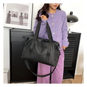 Detail of black waterproof nylon travel bag showing buckles and adjustable shoulder strap