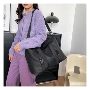 Detailed view of a large black travel tote bag with adjustable strap and buckle closure