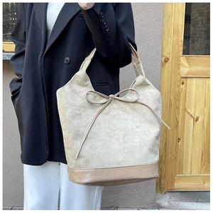 Detail of khaki tote bag featuring suede texture and decorative bow on shoulder strap