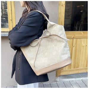 Side view of large beige suede tote bag with brown leather details on female model