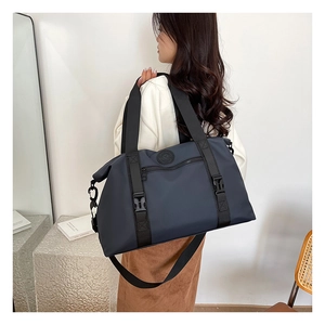 Detail of grey-blue waterproof travel bag with reinforced straps and logo on a stone stand