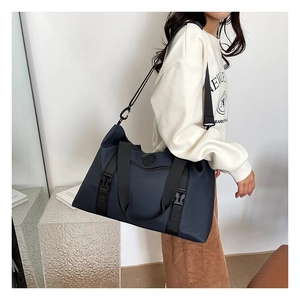Detail view of large navy travel bag with black buckle straps and textured surface