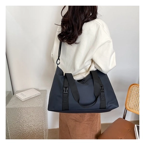 Deep blue nylon travel bag shown on a model featuring reinforced handles and side buckles