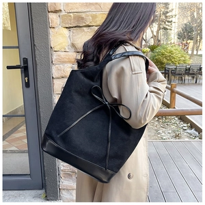 Detail of black tote bag featuring elegant bow tie decor and premium matte finish