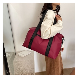 Detailed side view of a burgundy travel duffel bag with durable straps and waterproof fabric