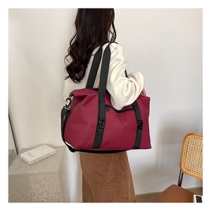 Detail of burgundy waterproof travel bag with dual handles and adjustable shoulder strap