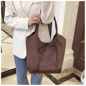 Detail of coffee brown suede tote bag with bow tie decoration and reinforced leather bottom