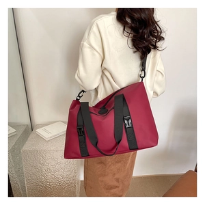 Rear view of a burgundy travel tote bag with black straps on a person in a bright room