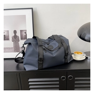 Detail of waterproof navy blue travel bag with durable black handles and shoulder strap