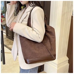 Detailed view of brown suede tote bag featuring leather patchwork and tassel drawstring