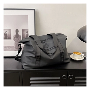Detail of black nylon travel bag with shoulder strap on a black metal cabinet