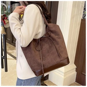 Detail of dark brown suede tote bag with leather base and drawstring bow on model